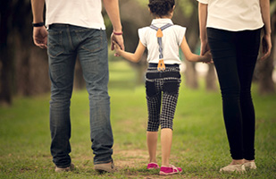 Image of a man and woman holding hands and walking with a young girl