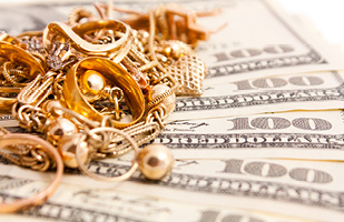 Image of a pile of gold jewelry sitting on top of paper money (iStock/Gerakl)