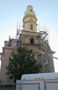 Image of the exterior of the Logan County courthouse with scaffolding in front of it as it undergoes repairs