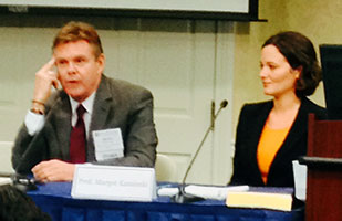 Image of a man and woman dressed in business attire participating in a panel discussion during a conference