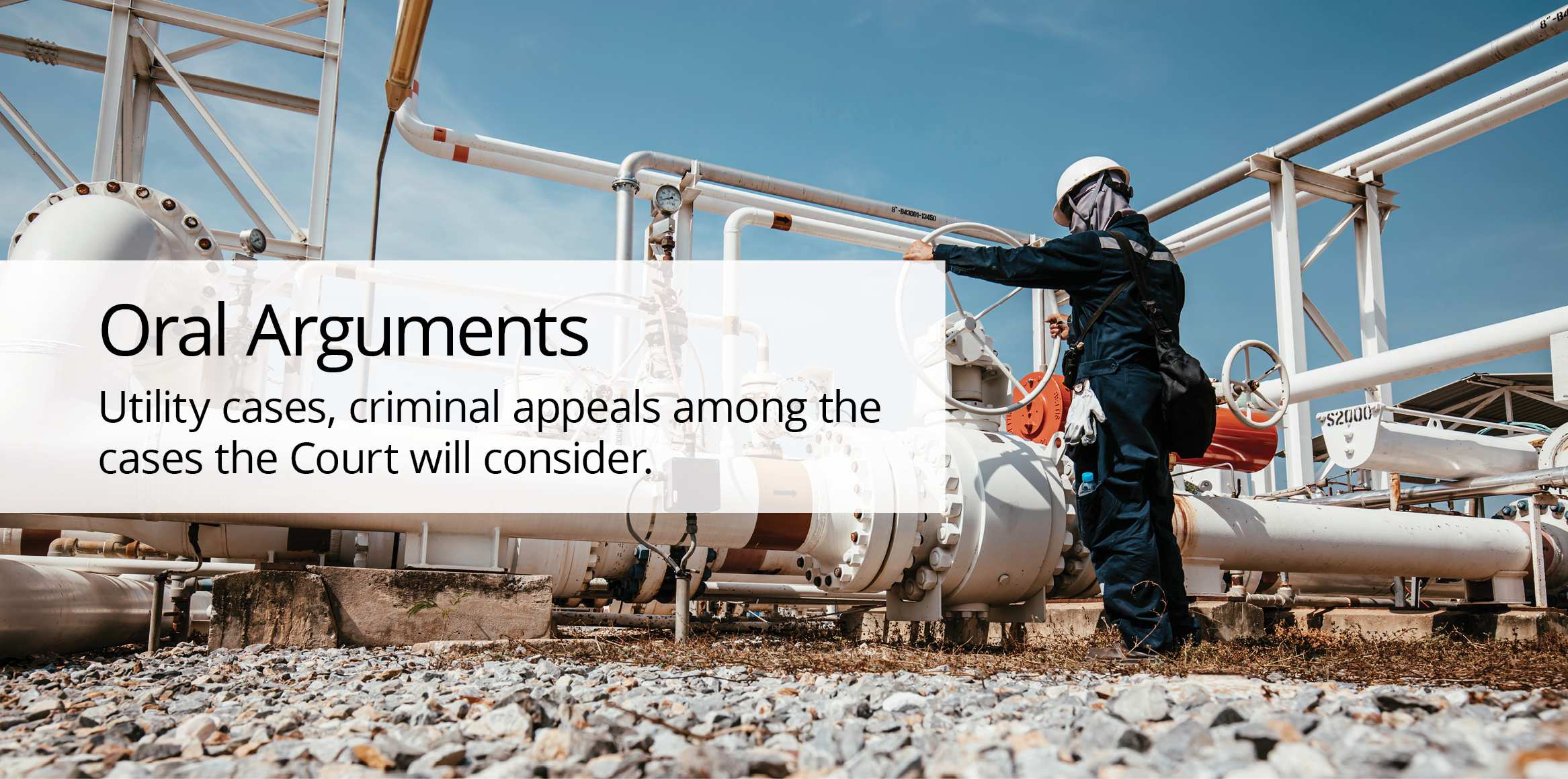 A worker wearing a blue jumpsuit and white hard hat working on a gas line.