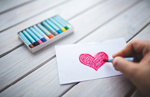 Image of a person coloring a heart on a piece of paper