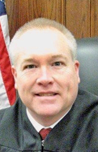 Image of a male judge wearing a black judicial robe