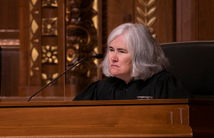 White woman with grey hair in a black judicial robe sitting behind a bench.