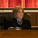 Image of female judge in a judicial robe holding an award. On either side of her is a man and a woman.