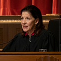 Image of a female judge wearing a black judicial robe sitting on the bench in the courtroom of the Thomas J. Moyer Ohio Judicial Center