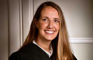 Image of a smiling female judge with long, straight blonde hair.