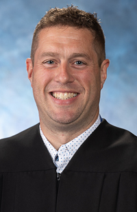 Image of a male judge wearing a black judicial robe.