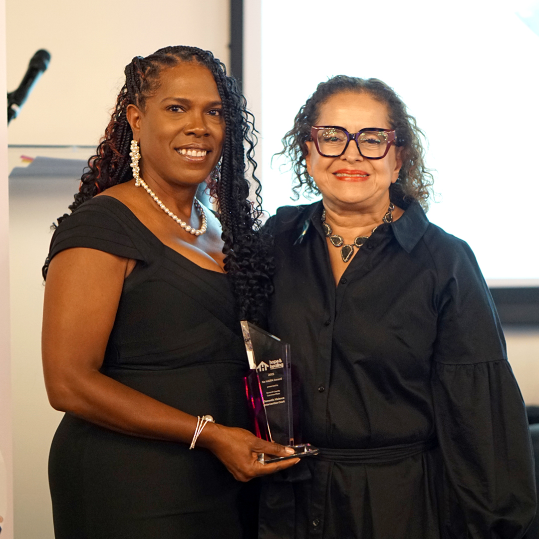 Two women smiling holding an award