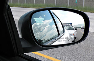 Image of a police cruiser as seen in a car's side mirror (Photo Credit: Derek Miller/Thinkstock)
