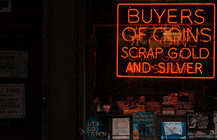 Image of a pawn shop storefront showing a neon sign that reads 'Buyers of Coins Scrap Gold and Silver' (Osman Rana/Unsplash)