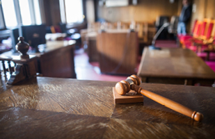 Image of a wooden judge's courtroom bench with a wooden gavel sitting on the bench
