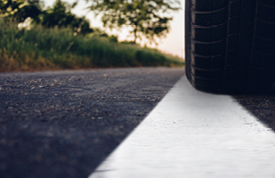 Image of a car tire just over the white line on a road