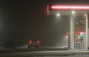 Image of a gas station at night time, with two cars in its parking lot