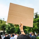People holding cardboard signs in protest outdoors.
