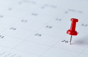 Image of a red thumbtack sticking out of a calendar on the 26th day of the month.