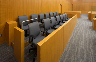 Image of two rows of empty chairs in a jury box in a courtroom.