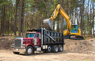 Image of a dump truck being loaded by an excavator truck.