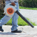 Image of a man's legs walking carrying a leaf blower.