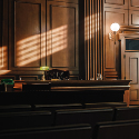 Image showing a dimly lit courtroom and an empty judicial bench.