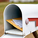 Image of a white mailbox with the door open and various pieces of mail inside.