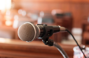 Image of a microphone attached to a mounted microphone stand in a courtroom.