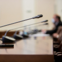 A row of microphones on a long, wooden table.