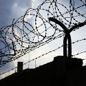 Barbed wire attached to the top of a prison wall.