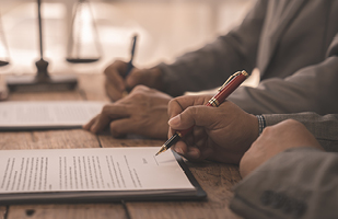 Image showing a hand holding a pen about to sign a paper.