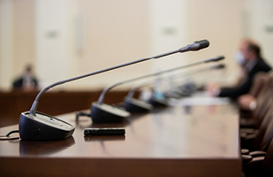 A row of microphones on a long, wooden table.