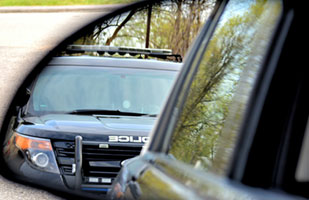 Image of a police cruiser as seen in someone's side mirror.