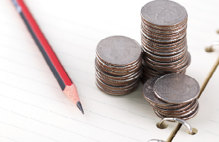 Image of stacks of quarters next to a pencil sitting on an open notebook.