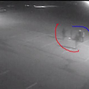 Grainy surveillance image of several people standing in an empty parking lot at night.