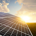 A large solar panel in a large field with the sun reflecting off of it.