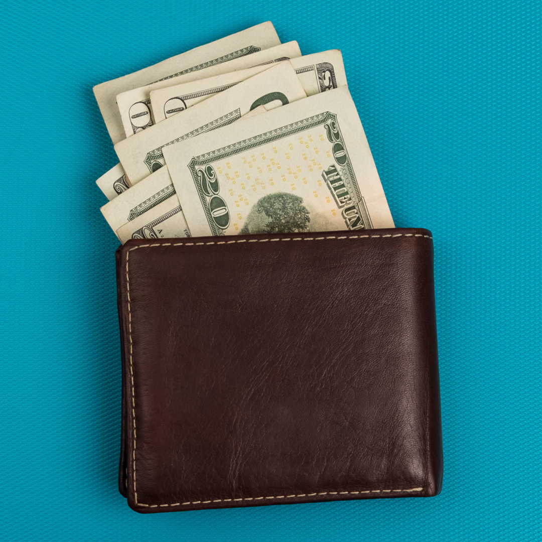 A man's wallet with bills in various denominations sticking out of it.