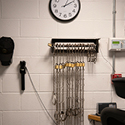 A white cinder block wall on which is hanging a rack of prisoner shackles.
