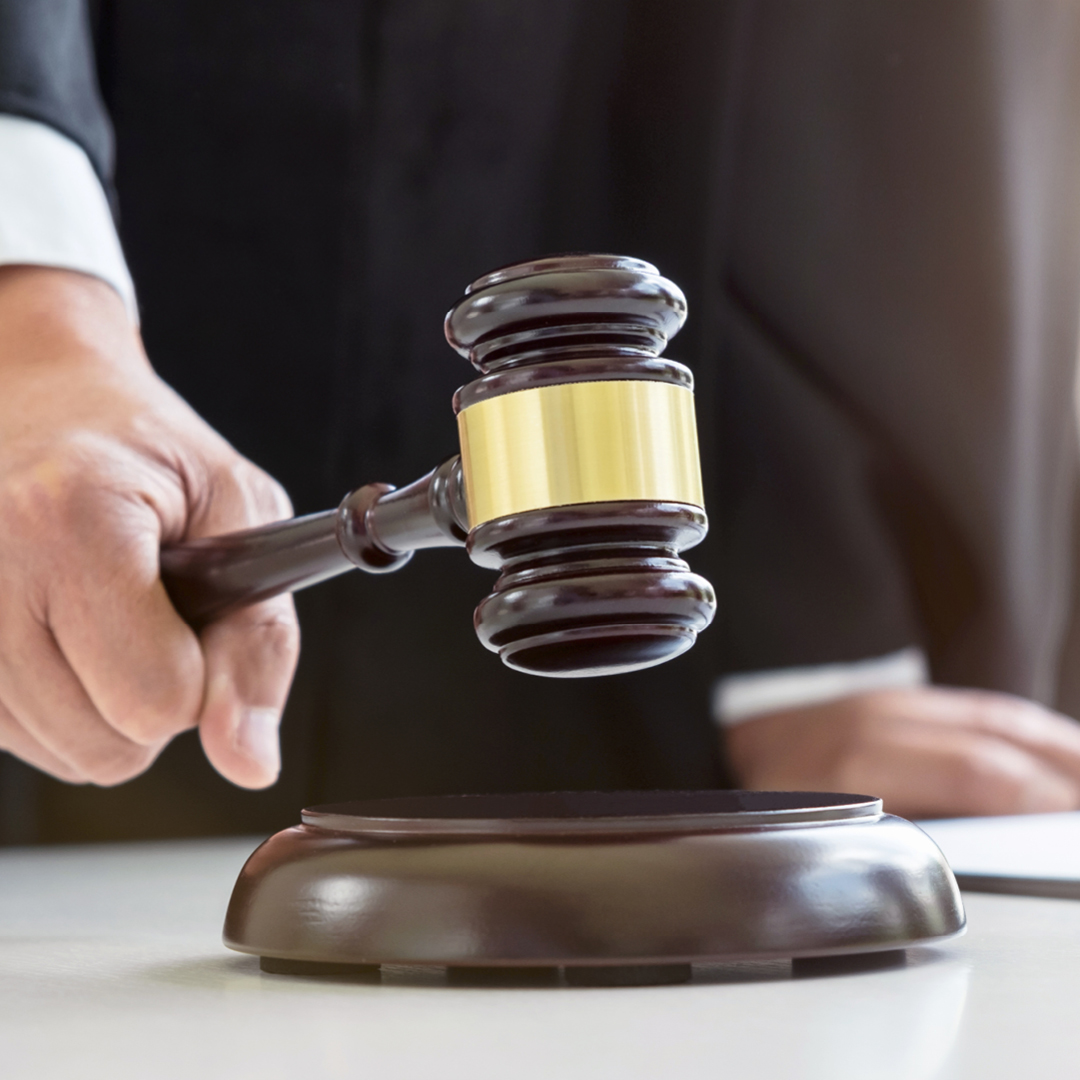 A hand hitting a wooden gavel on a wooden sound block.