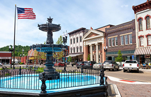 The center of a small town with a decorative foutain and an American flag.