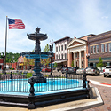 The center of a small town with a decorative foutain and an American flag.