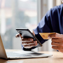 A person holding a cellphone in one hand and a credit card in the other.