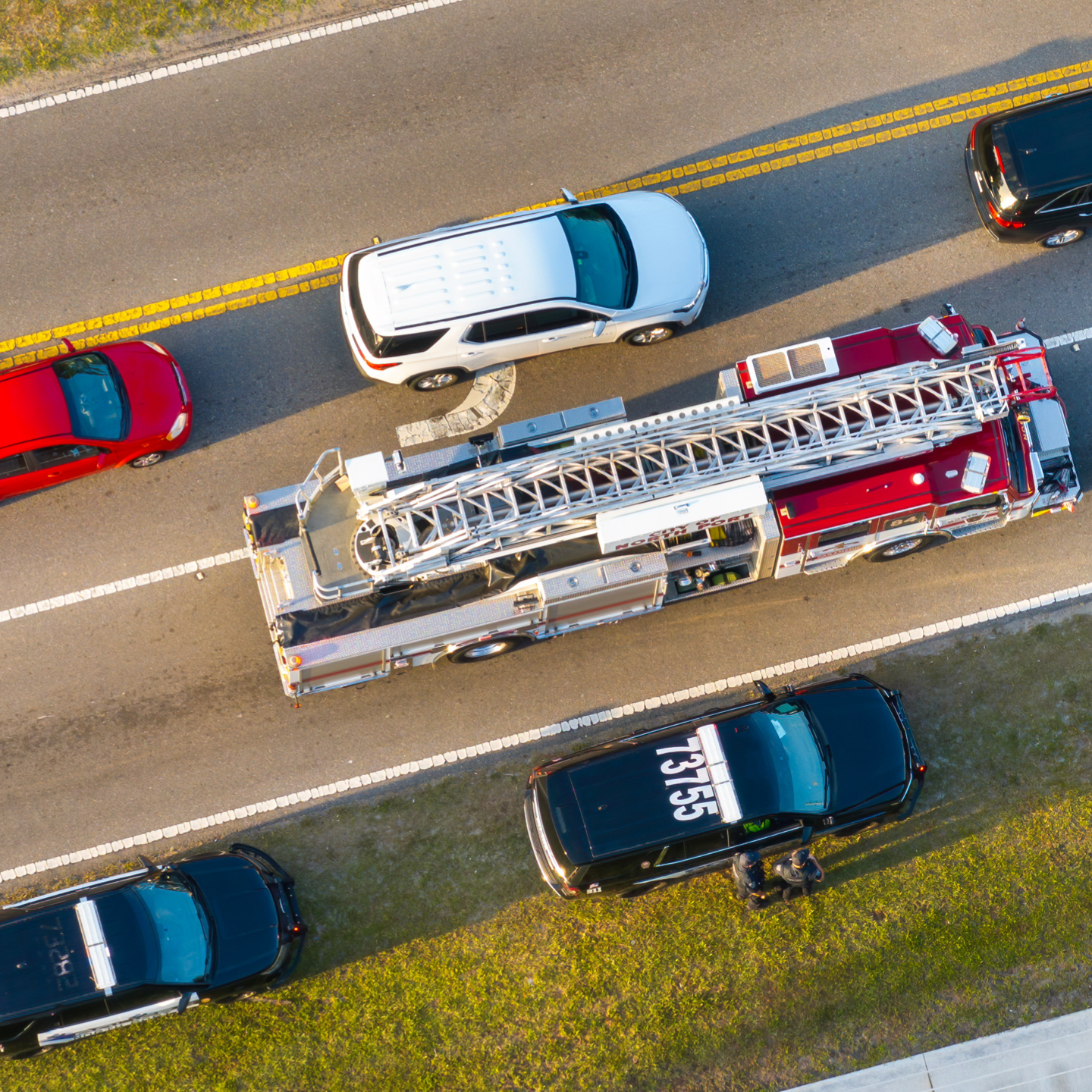 A ladder fire truck on a highway surrounded by cars