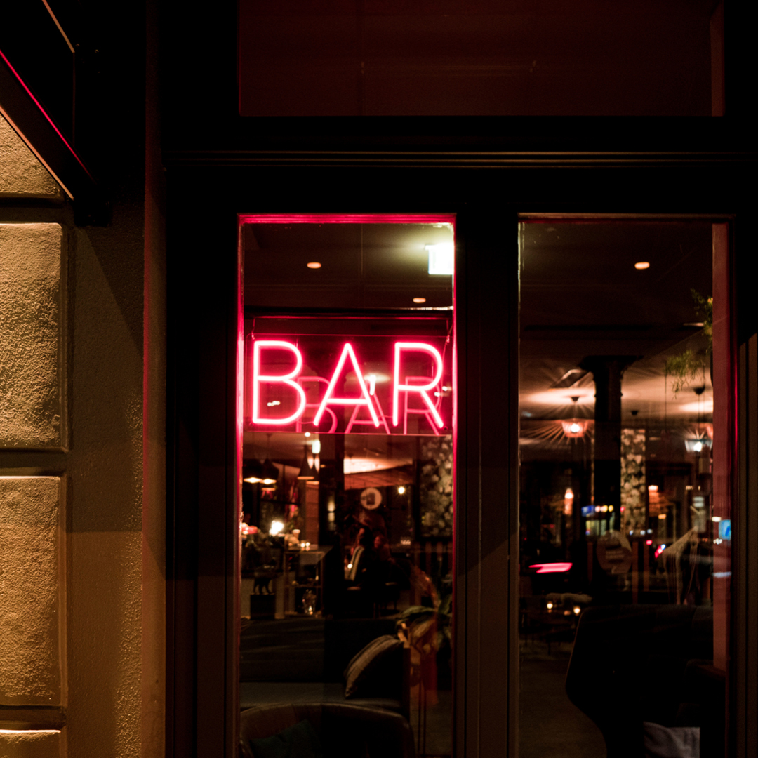 A neon sign reading 'bar' in a window of a bar