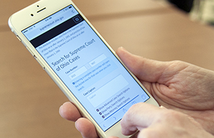 Image of hands holding a smartphone with the redesigned Supreme Court online case management system on the screen