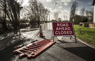 Image of a flooded roadway behind a 'Road Closed Ahead' warning sign (Thinkstock)
