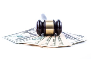 Image of a stack of fanned-out money underneath a gavel