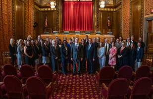 Image of a group of men and women in business attire gathered in the courtroom of the Thomas J. Moyer Ohio Judicial Center