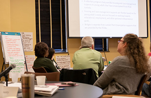 Image of people sitting at table listening to a seminar presentation