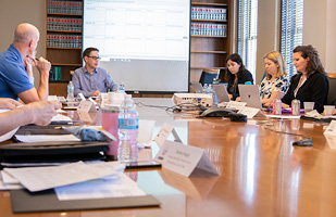 Image of a group of men and women meeting around a conderence table