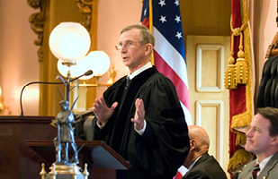 Image of the late chief justice in his judicial robe, speaking at the lecturn of the Ohio House of Representatives