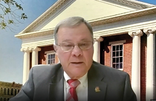 Image of a man in a suit with a brick building in the background